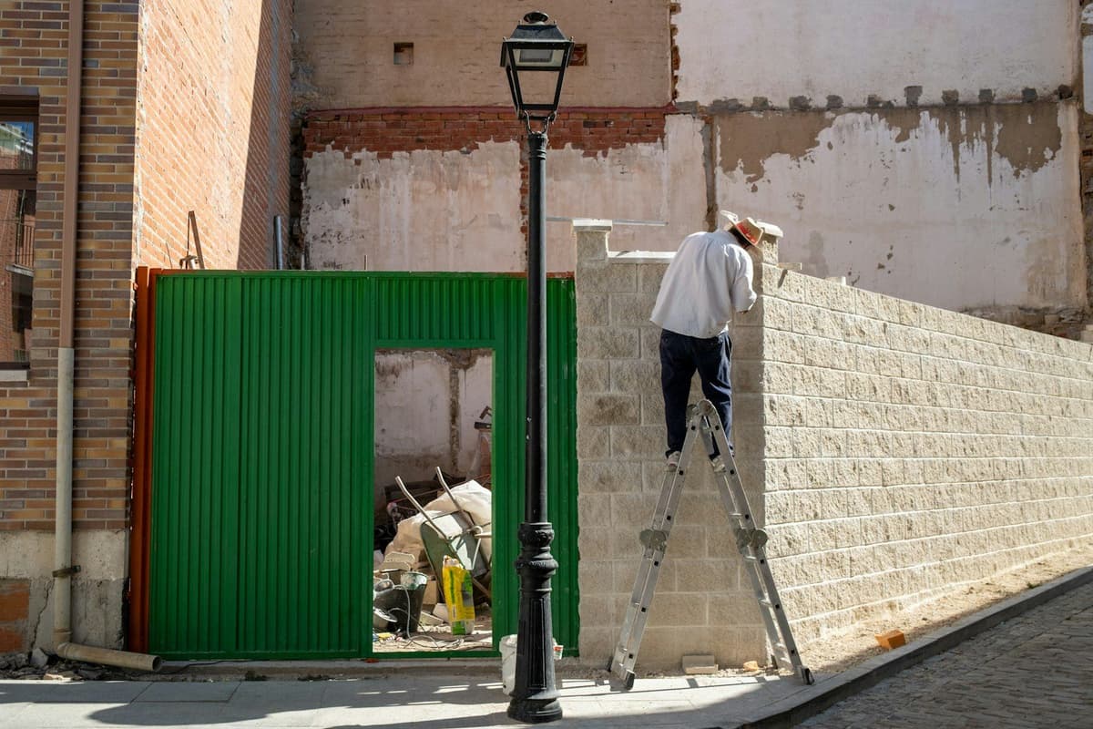 A man standing on a ladder next to a building